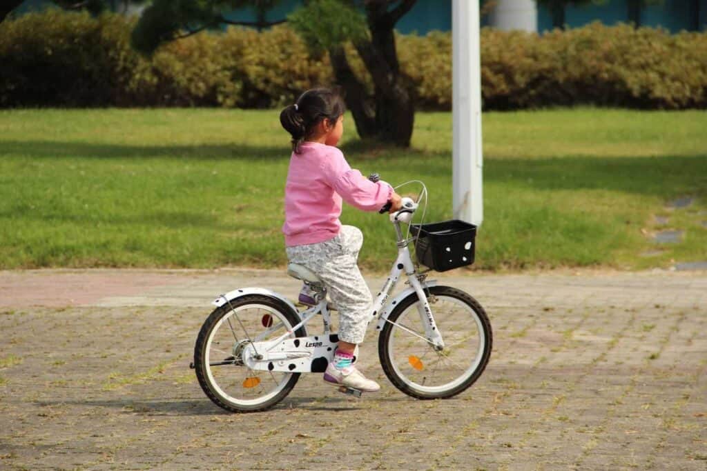girl in pink jacket riding bicycle during daytime