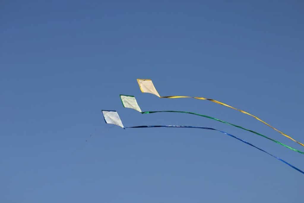 three kites under blue sky during daytime