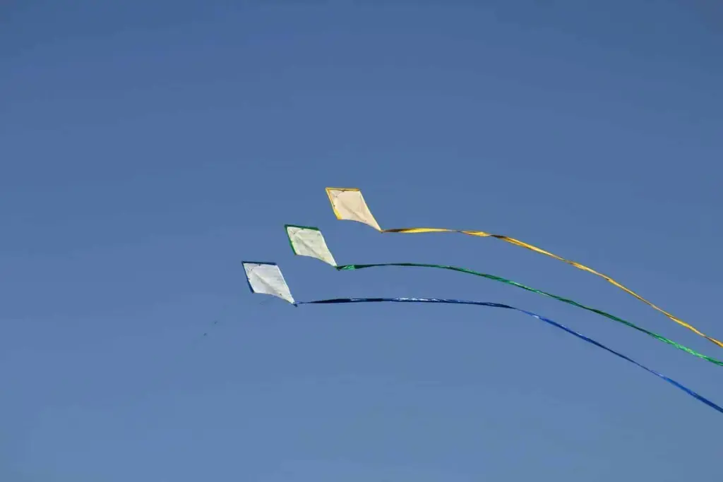 three kites under blue sky during daytime